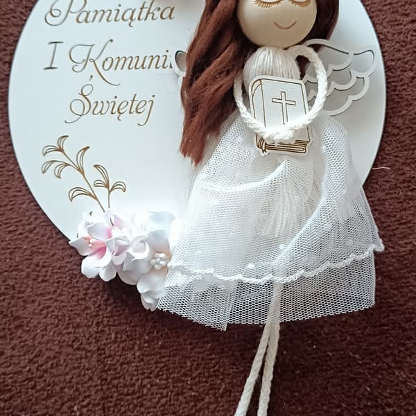 Aniołek komunijny, biały, z drewna i tkaniny, z napisem "Pamiątka I Komunii Świętej".